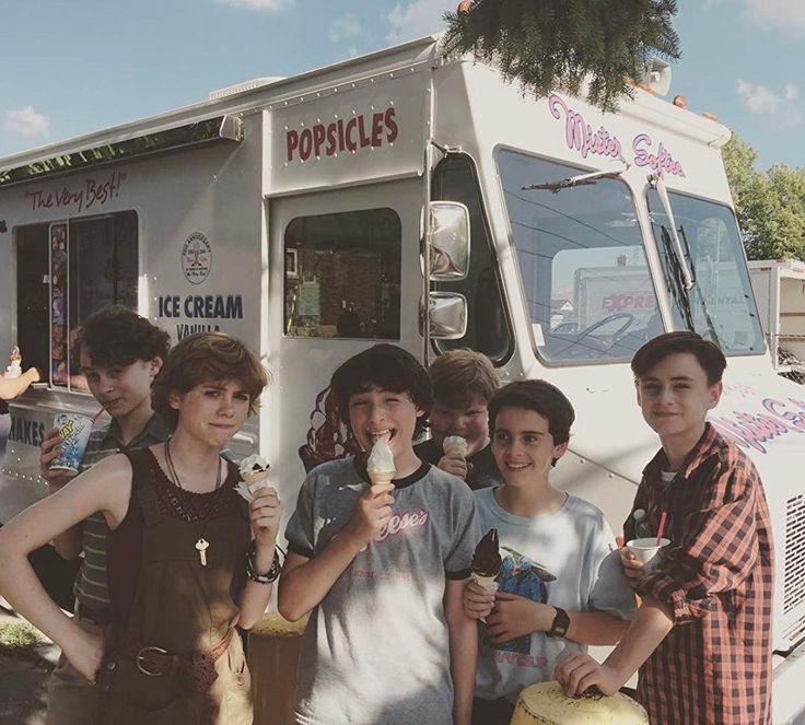 a group of young men standing next to each other in front of a food truck