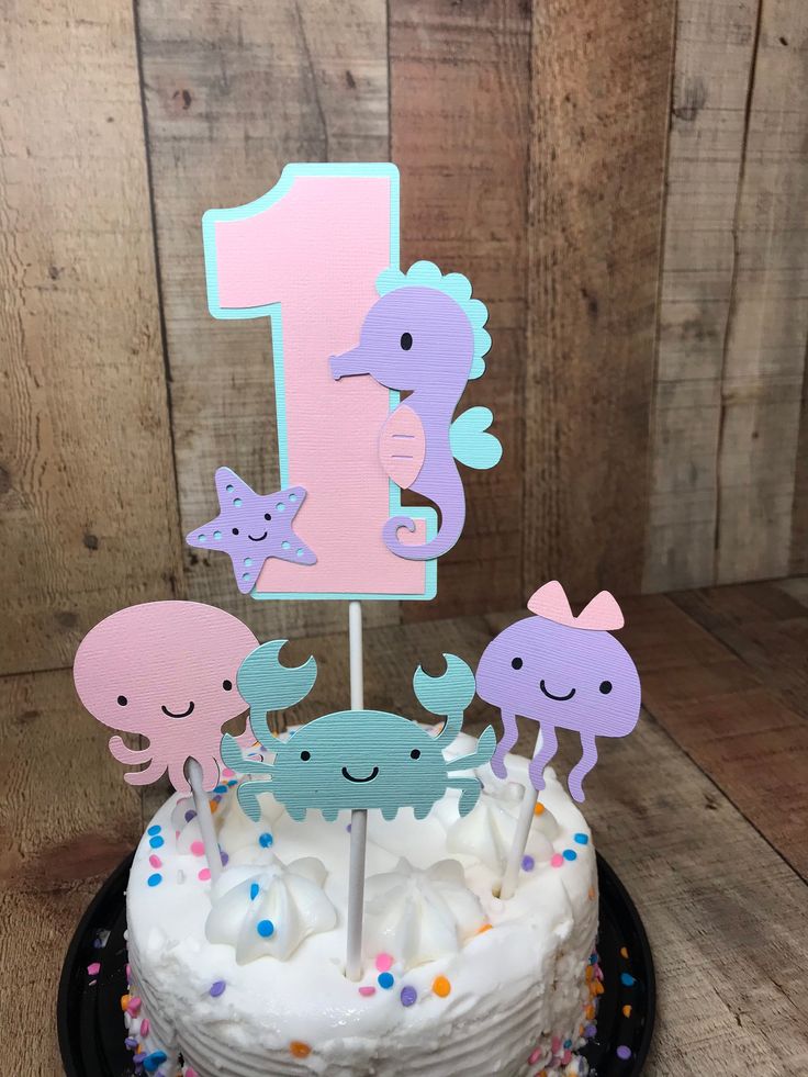 a birthday cake decorated with sea animals and one candle for the number one on top