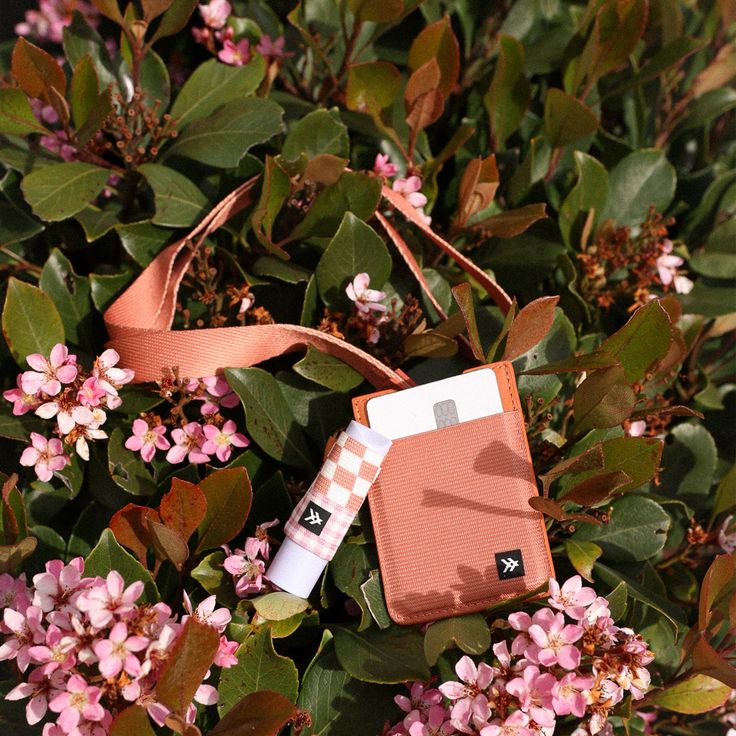 an orange and white bag sitting on top of some pink flowers