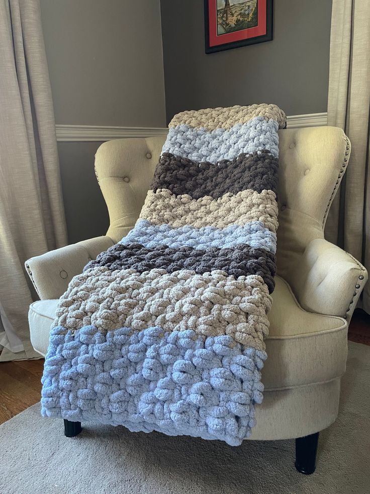 a white chair with a blue and gray blanket on it