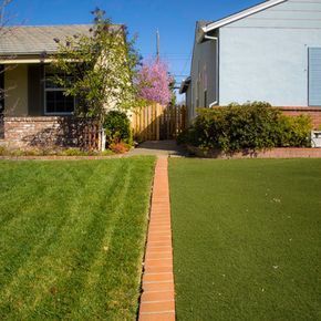 a yard with grass and brick walkway leading to a house in the background, on a sunny day