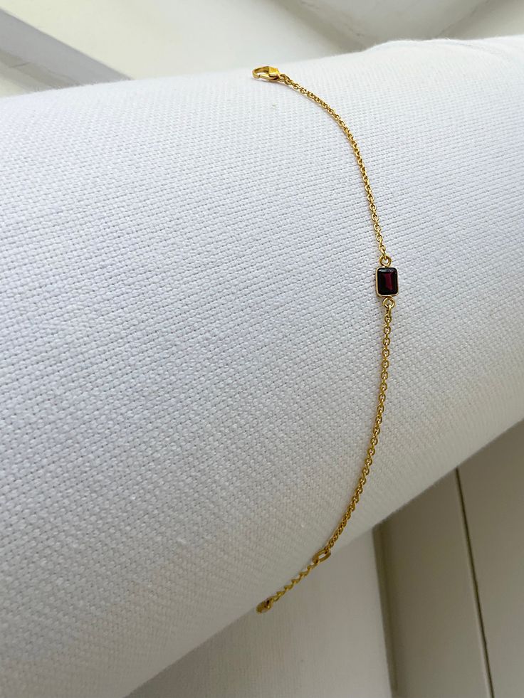 Ring chain bracelet with a rectangular garnet stone charm - Approx .45" garnet encased stone charm - 6" with 1" adjustable chain - 18 karat gold plated brass - Each order comes in a velvet pouch in our signature box, perfect for gifting. Jewelry With Adjustable Chain And Rectangular Links As Gift, Gift Jewelry With Adjustable Chain And Rectangular Links, Dainty Jewelry With Rectangular Stone For Everyday, Gold Plated Rectangular Links Jewelry For Gifts, Minimalist Jewelry With Rectangular Birthstone, Formal Jewelry With Adjustable Chain And Rectangular Shape, Minimalist Rectangular Birthstone Jewelry, Adjustable Dainty Ruby Jewelry, Gold Plated Gemstone Jewelry In Rectangular Shape