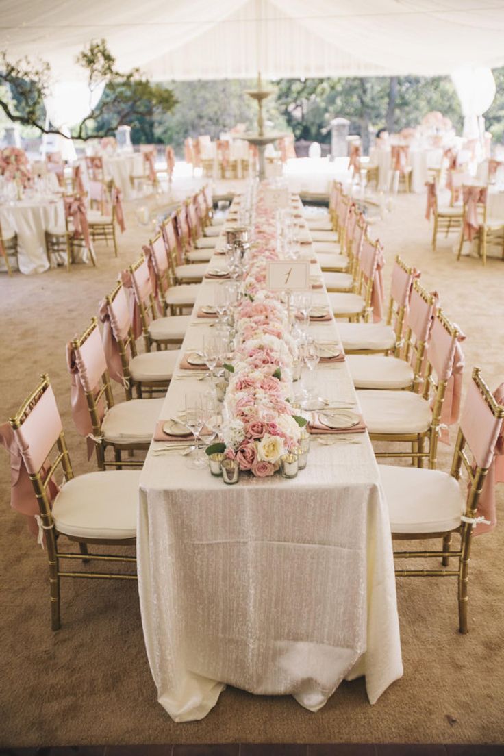 a long table is set up with white linens and pink flowers