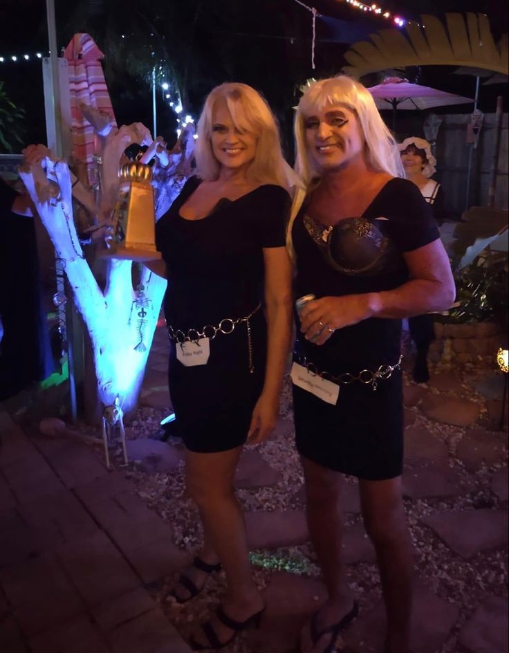 two women standing next to each other in black dresses