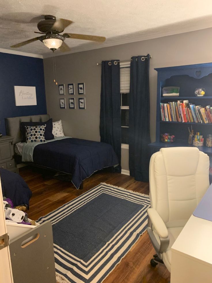 a bedroom with two beds, a desk and a book shelf in the corner is shown