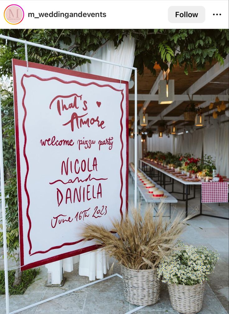 a sign that is on the side of a building with flowers in baskets next to it