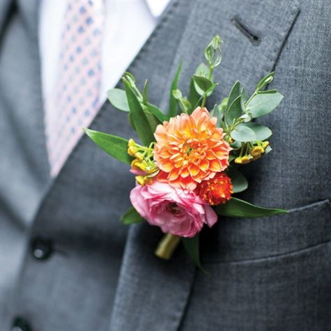 a boutonniere with orange and pink flowers is on the lapel of a man in a suit