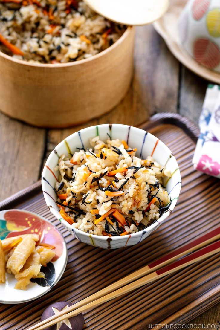 two bowls filled with food sitting on top of a wooden table next to chopsticks