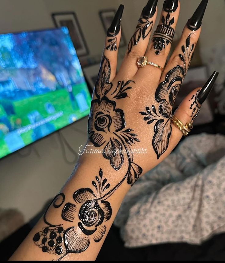 a woman's hand with black and white tattoos on it, next to a tv