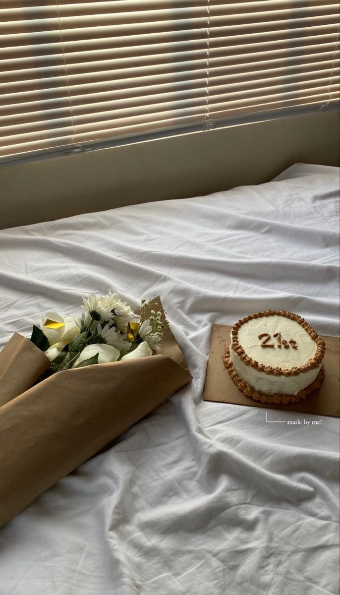 a cake and flowers sit on a bed