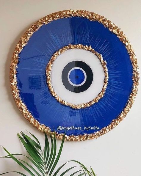 a blue and gold plate with an evil eye on the side next to a potted plant