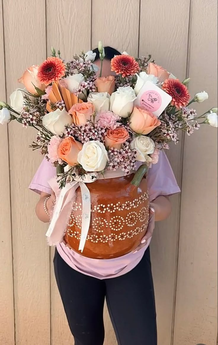 a woman is holding a large vase with flowers on it's back and wearing leggings