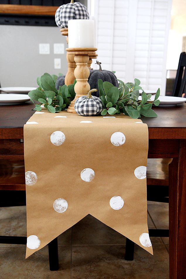 a table topped with a brown paper bag covered in white polka dots and pumpkins