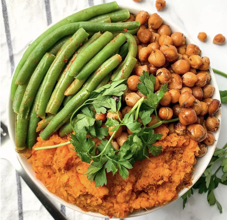 a white bowl filled with mashed potatoes, green beans and garbanzo sprinkled with parsley