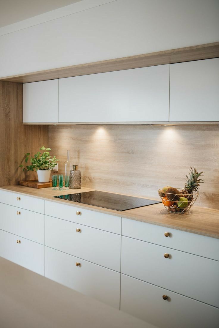 a kitchen with white cabinets and wooden counter tops, plants on the stove top in front of the sink