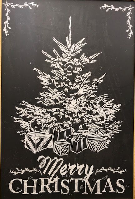 a chalkboard sign with a christmas tree and presents on it's black board