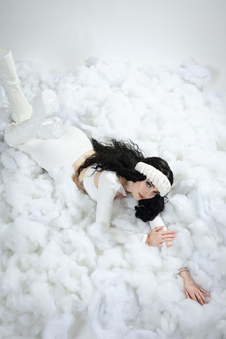 a woman laying on top of a pile of white fluffy material