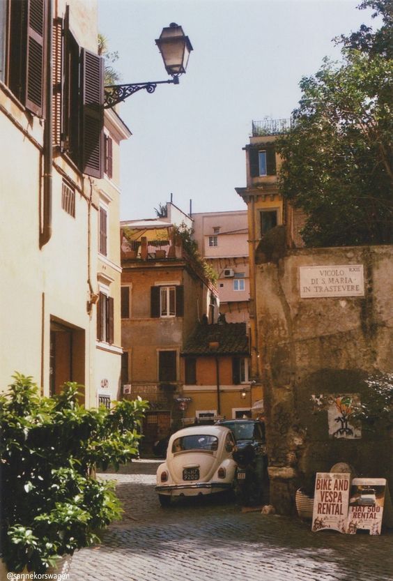 an old car parked on the side of a cobblestone street