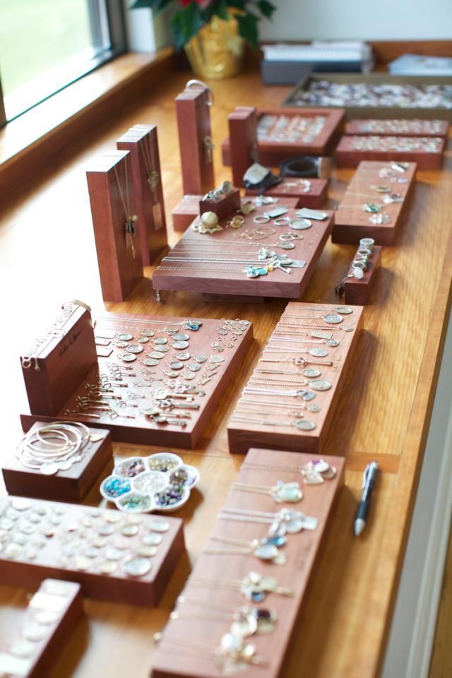 several pieces of jewelry sit on a table next to a window with a plant in the background