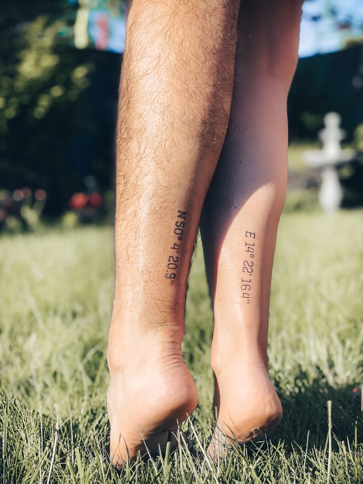 the legs of a person with tattoos on their ankles, standing in grass and looking down at the ground