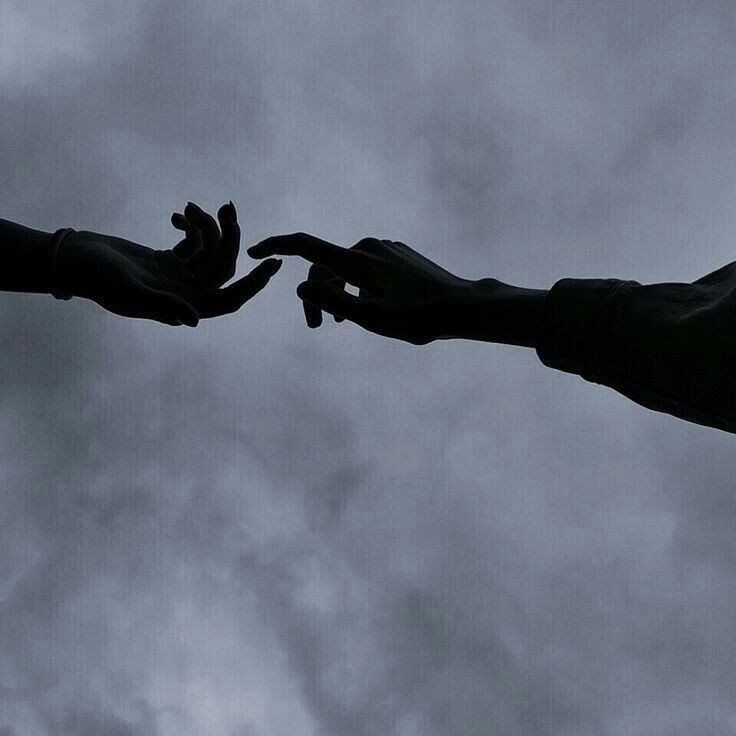 two hands reaching out towards each other in front of a cloudy sky with dark clouds