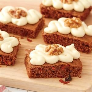 several pieces of brownies with white frosting and walnuts on top sitting on a cutting board