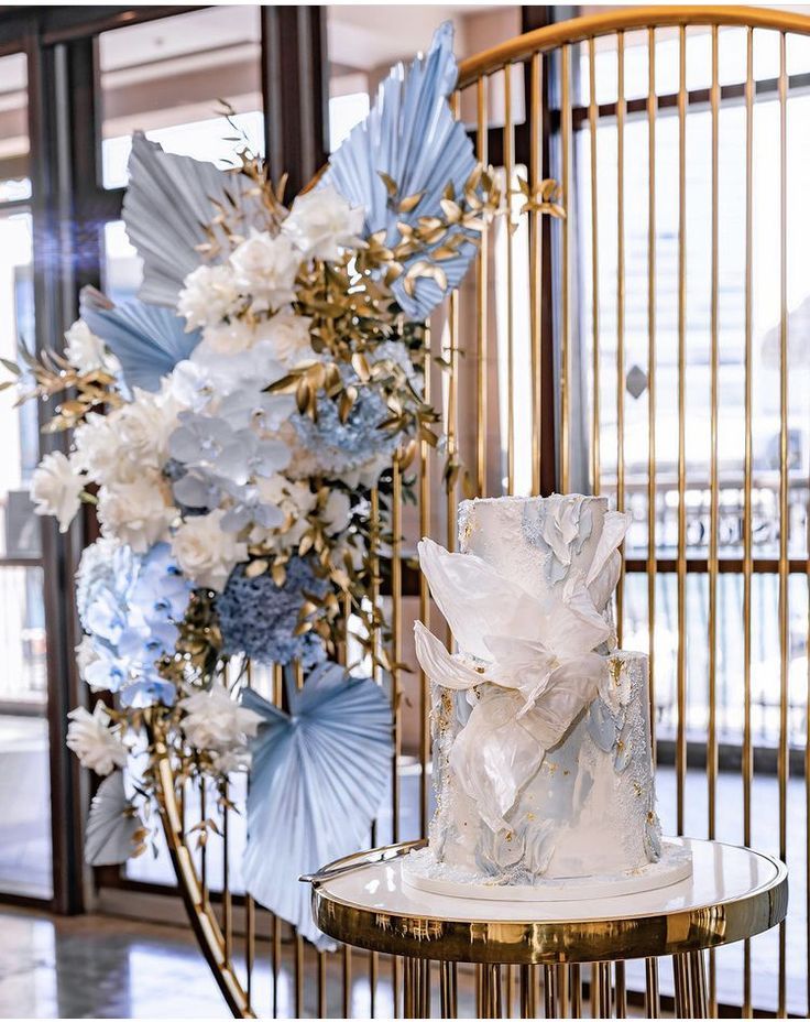 a white wedding cake sitting on top of a table next to a vase with flowers