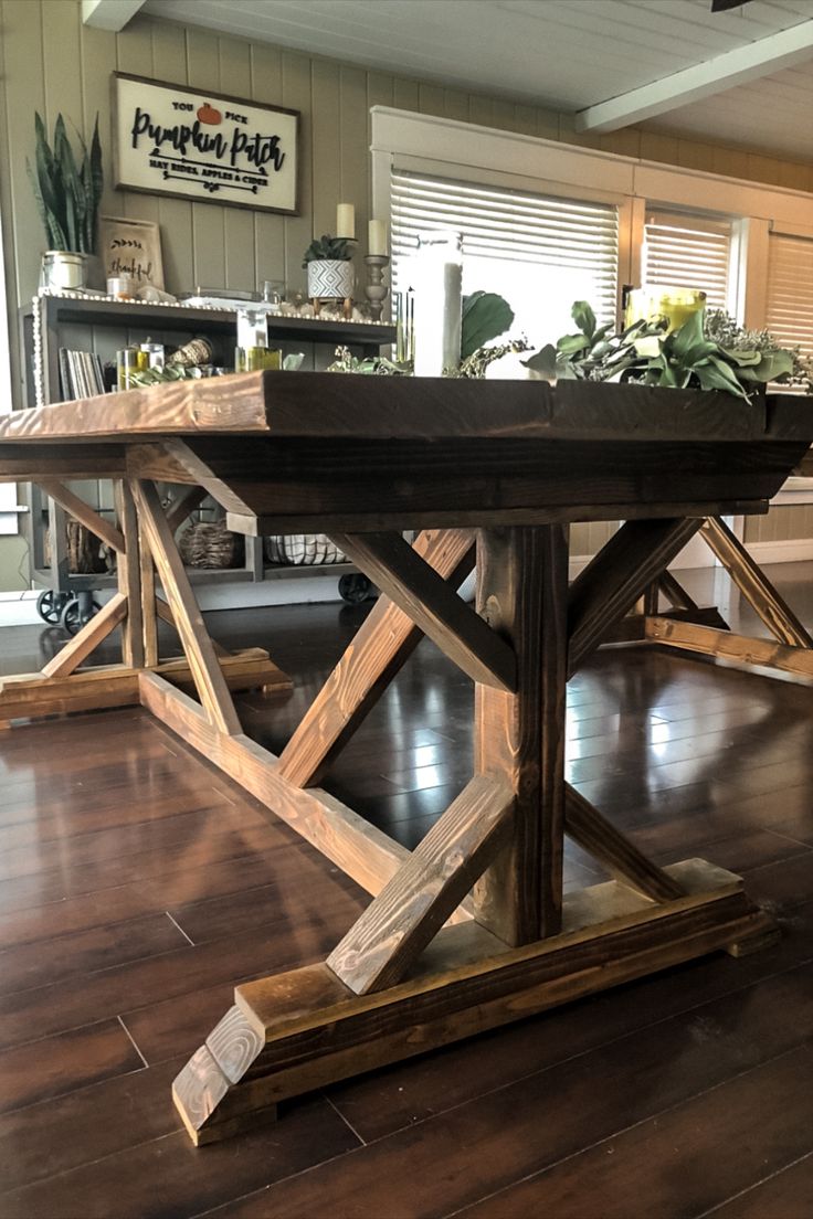 a wooden table sitting on top of a hard wood floor covered in potted plants