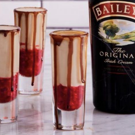 three shot glasses filled with liquid next to a bottle of bailey's irish cream