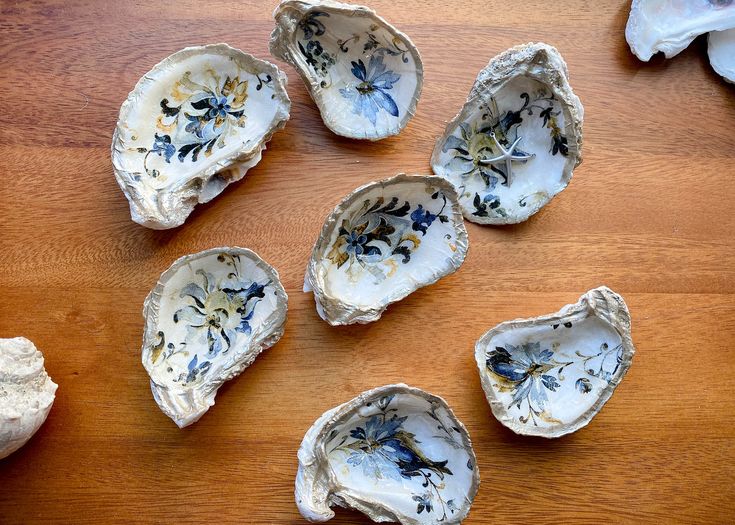 six oysters with flowers on them sitting on top of a wooden table next to shells