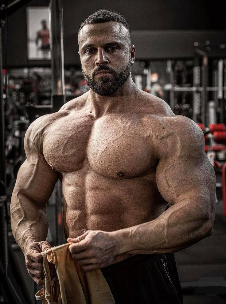 a shirtless man holding a bag in a gym