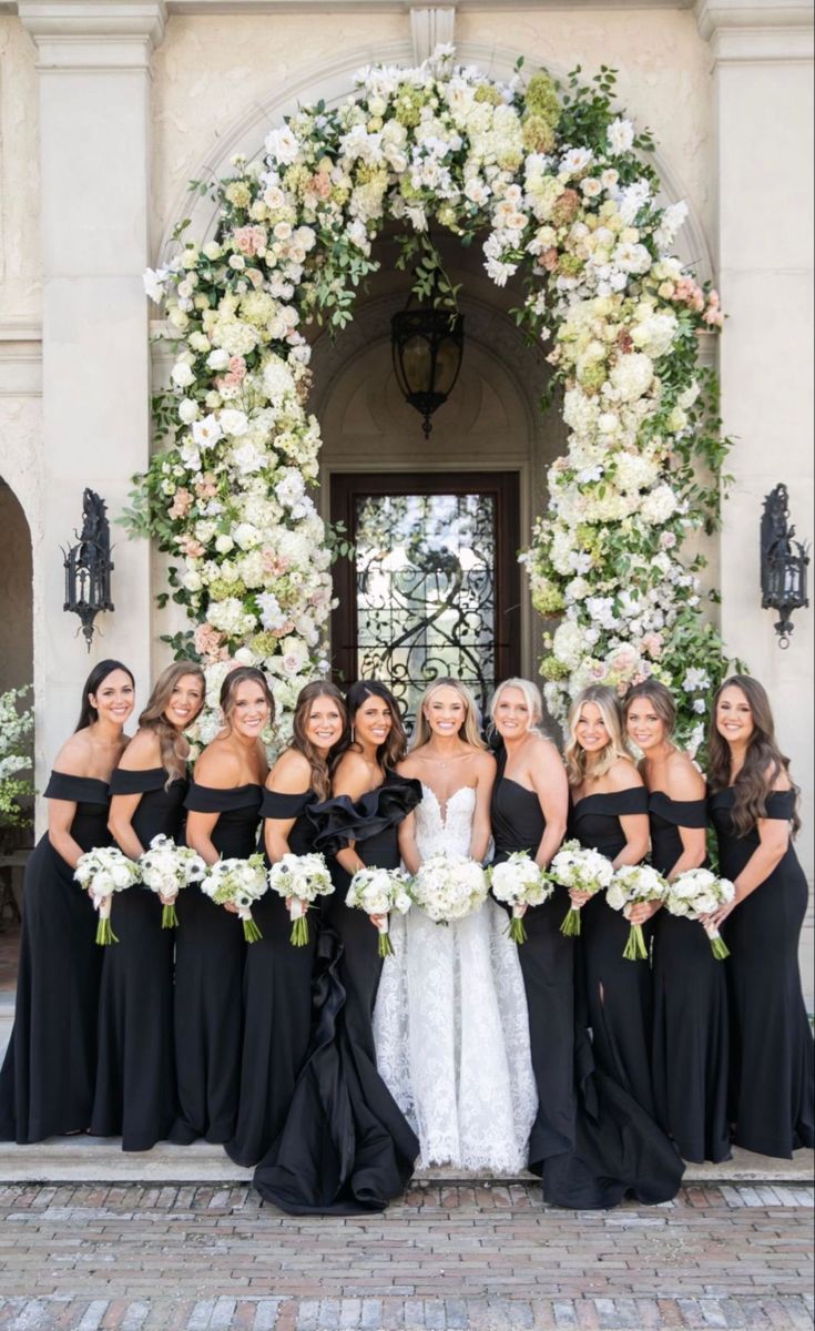 a group of women standing next to each other in front of a white and black arch