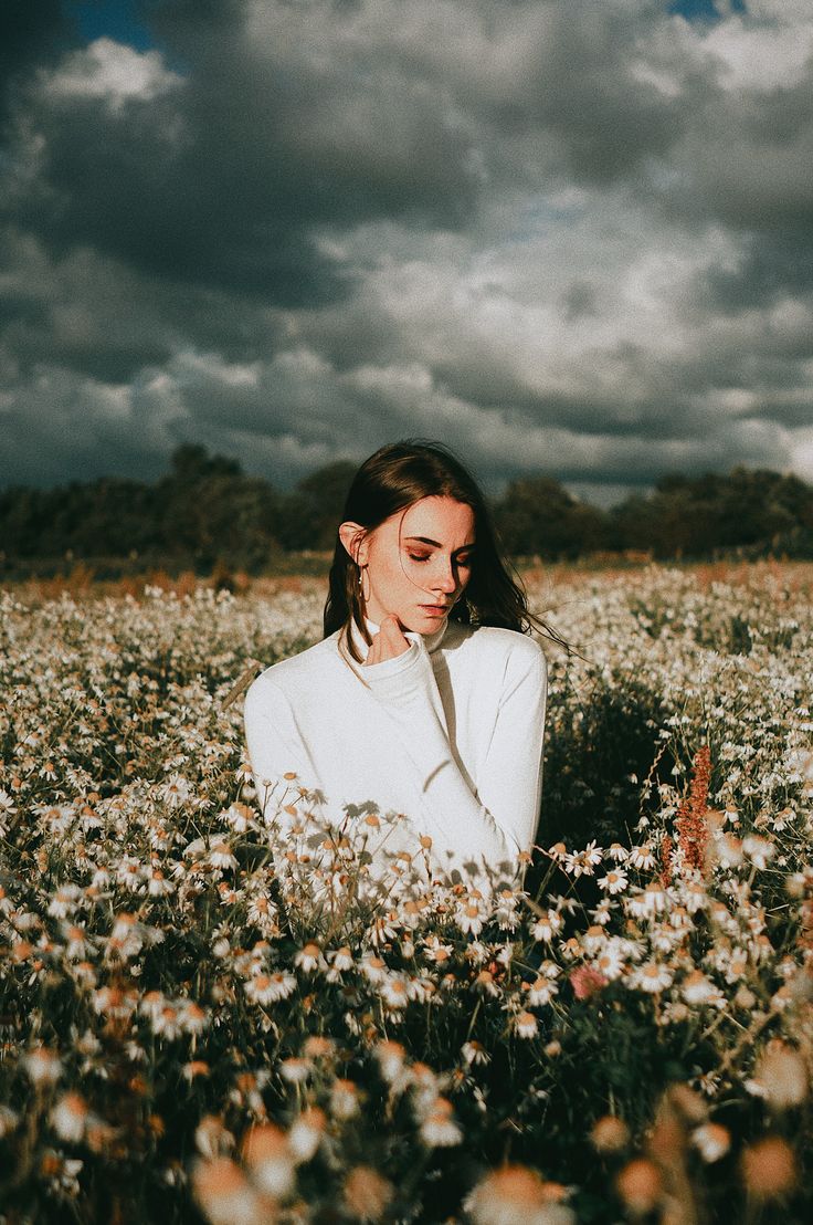 a woman is sitting in a field of flowers