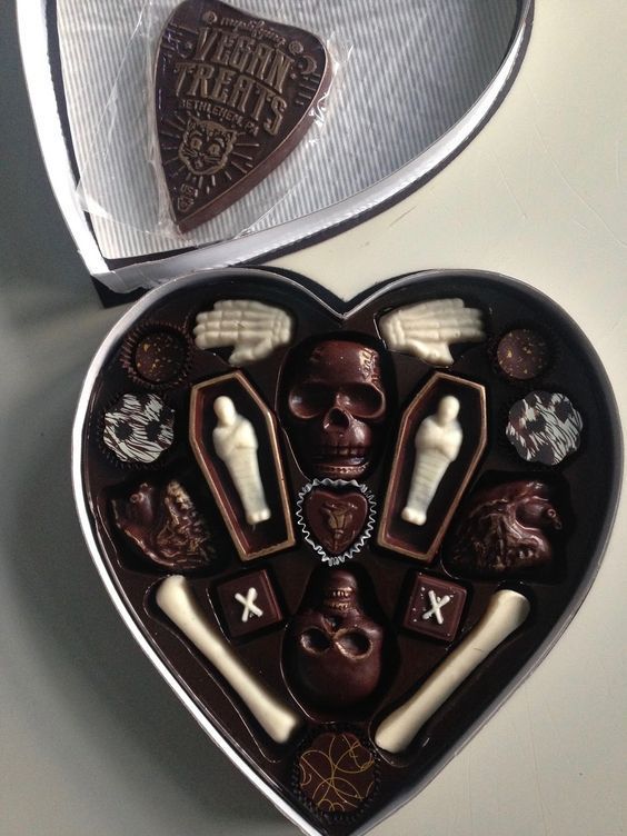 a heart shaped box filled with chocolates on top of a white table next to a knife