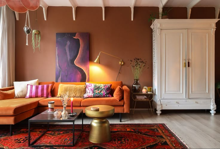 a living room with orange couches and rugs on the floor in front of a painting