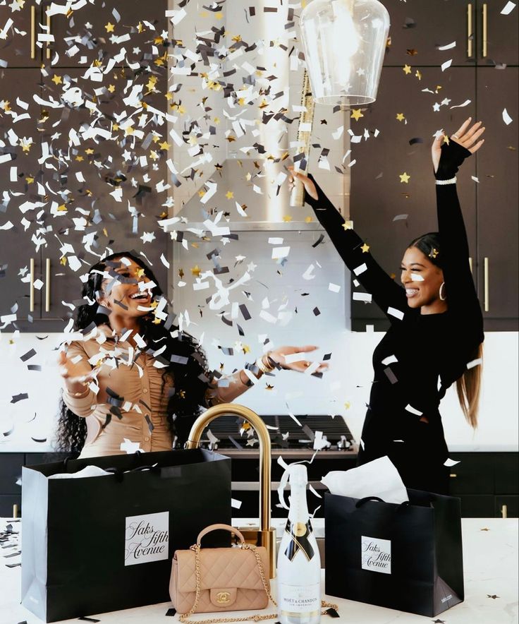 two women standing next to each other with confetti in the air