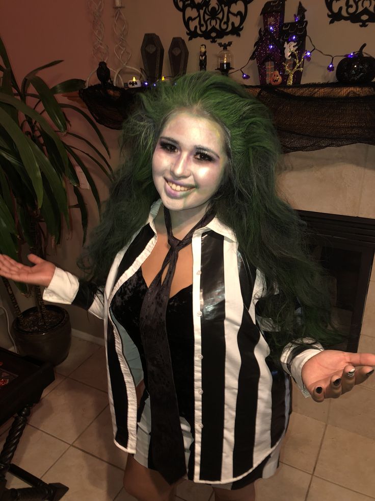 a woman with green hair and makeup posing for the camera