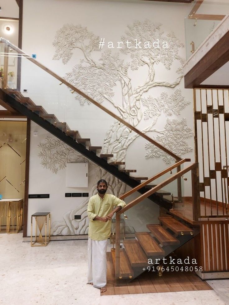 a man standing in front of a stair case next to a tree on the wall