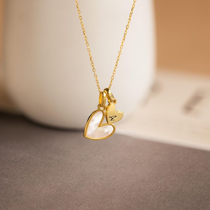 Celebrate love and elegance with our Stylish Pearl Initial Heart Necklace, featuring a custom initial heart charm alongside a lustrous pearl heart charm. This necklace beautifully combines the timeless appeal of pearls with the romantic symbol of hearts, making it an ideal gift for someone special in your life. Perfect for anniversaries, birthdays, or just because, this charming piece adds a personal and sophisticated touch to any ensemble ♡ SKU: MM-NM163F47 Product Details Material: High Qualit Elegant Double Heart Charms Necklace, Anniversary Heart Pendant Pearl Necklace, Elegant Wedding Heart Necklace With Charms, Luxury Charm Necklaces With Heart Charm For Gift, Personalized Dainty Pearl Necklace For Anniversary, Luxury Heart Charm Necklace For Gift, Gold Pearl Necklace With Heart Charm For Anniversary, Heart-shaped Pearl Necklace For Anniversary, Heart Pendant Necklace With Pearl Charm For Anniversary