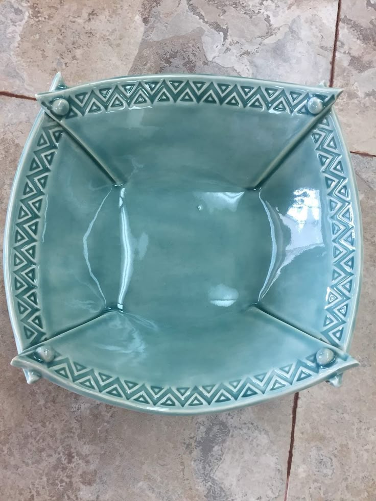 a green bowl sitting on top of a tile floor