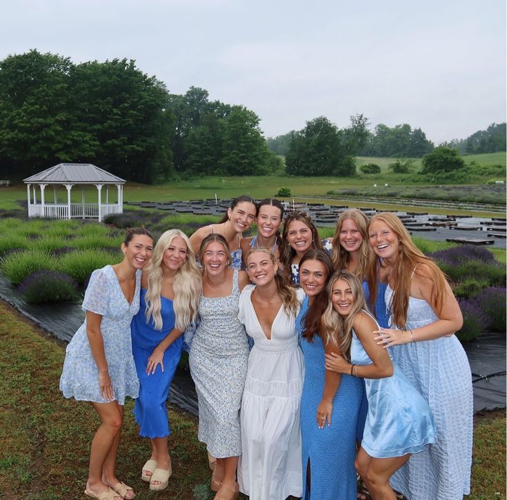 a group of young women standing next to each other in front of a garden area