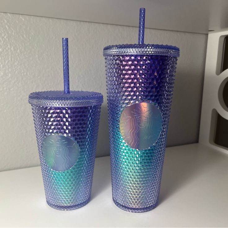 two purple and blue tumblers sitting next to each other on a white counter top