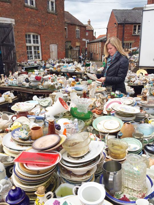 a woman standing in front of a table full of plates and bowls on top of it