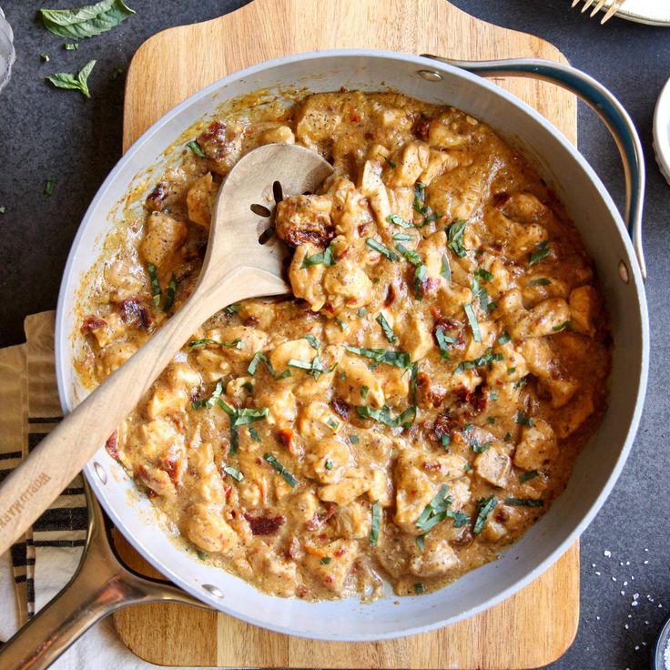 a wooden spoon in a white pan filled with food on top of a cutting board