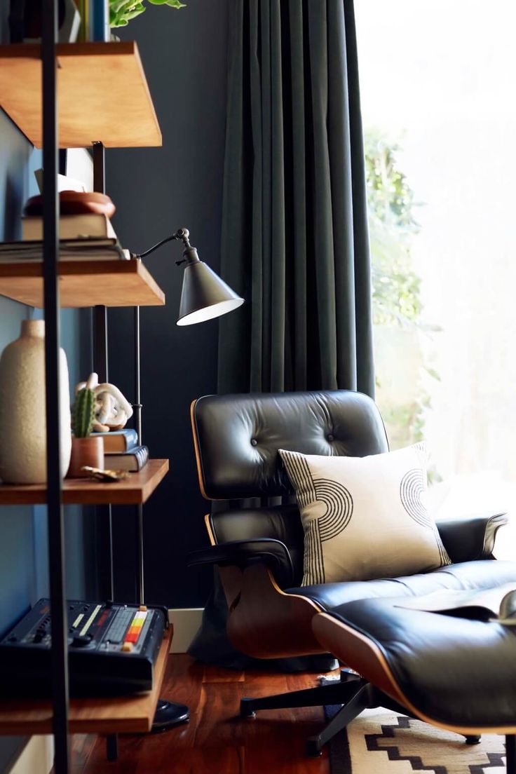 a living room with a chair, lamp and bookshelf in front of a window