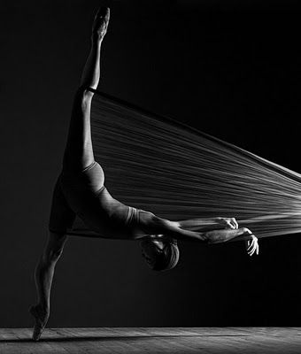 a woman is doing a handstand on the floor in front of a black background