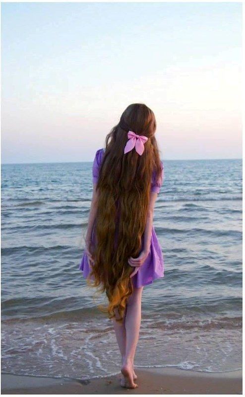 a girl with long hair standing on the beach