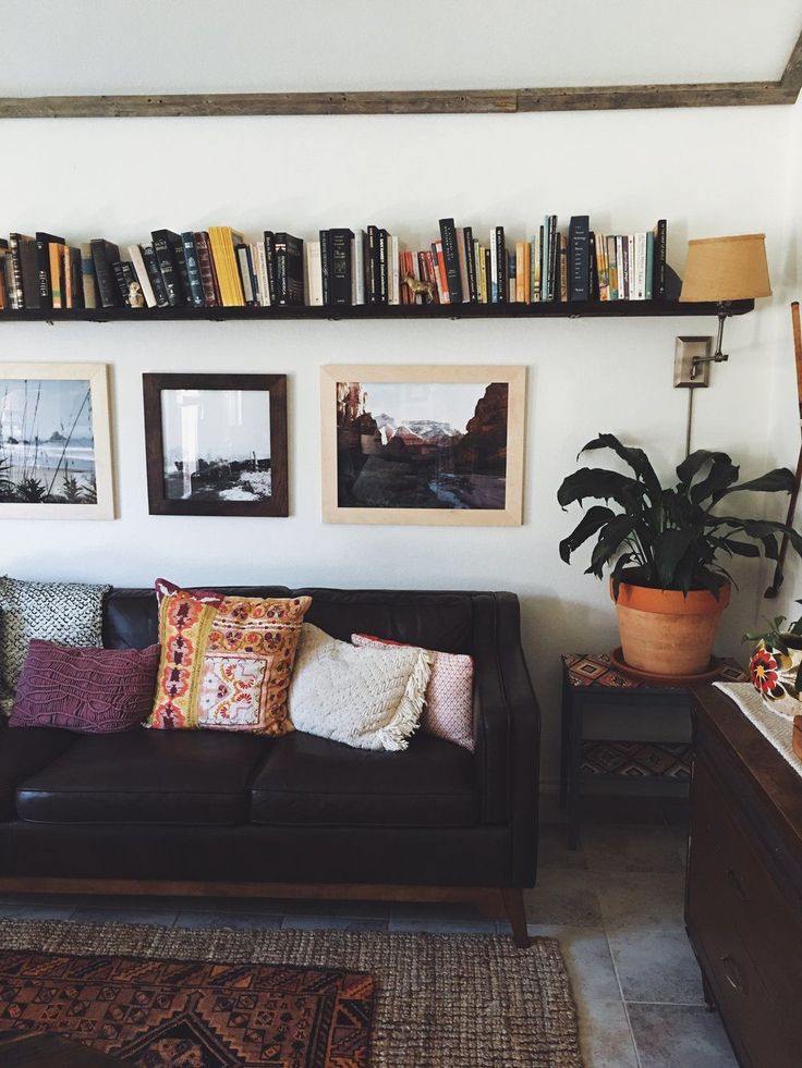 a living room filled with furniture and lots of books on the shelf above it's headboard