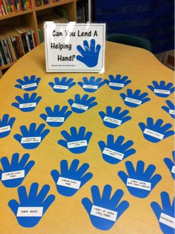 a table with blue handprints on it and a sign that says can you lend a helping hands?