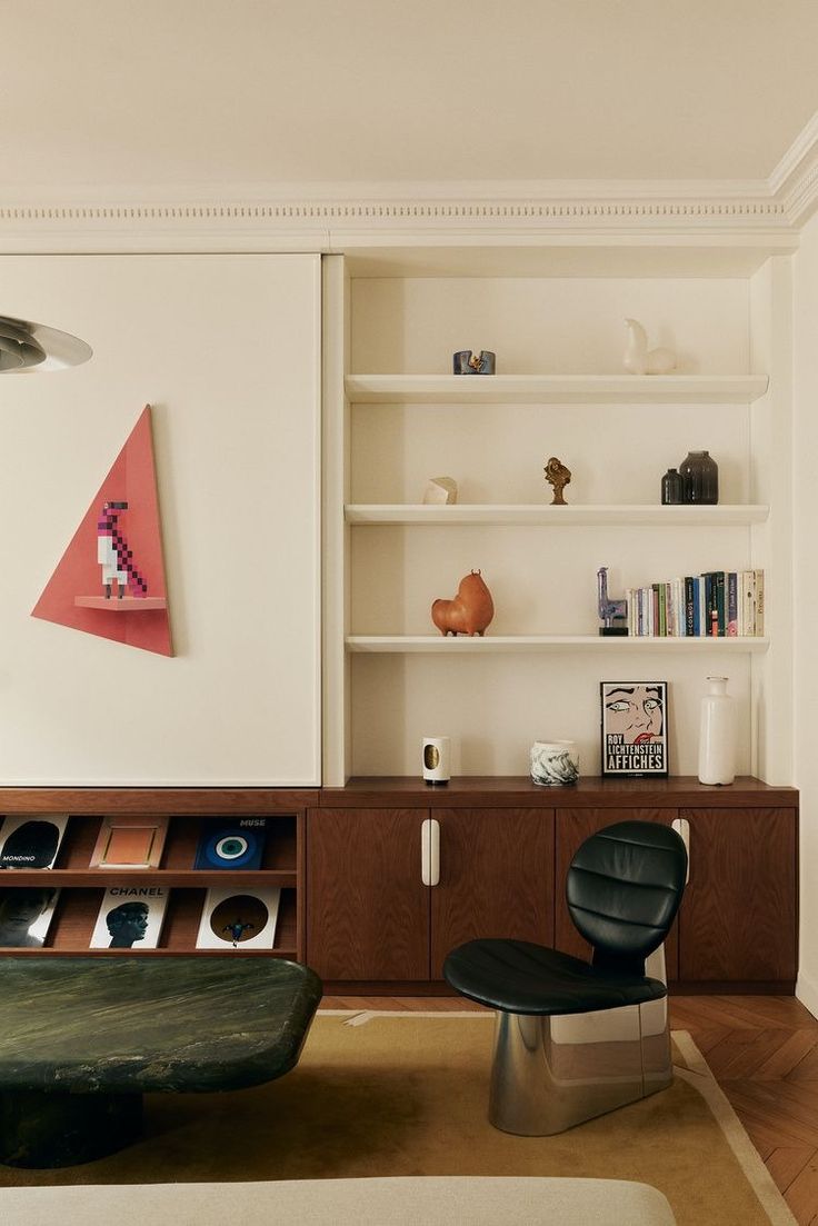 a living room filled with furniture next to a book shelf and shelves on the wall